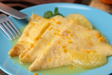 Plate with tasty crepes Suzette on table, closeup