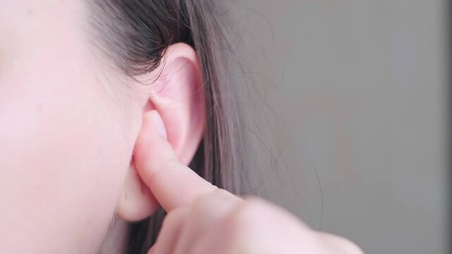 Woman inserting earplugs into her ears for sleep, work, travel, and noise protection.