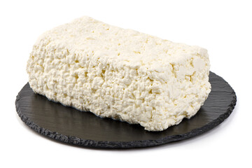 Fresh block of cottage cheese on a black slate plate, isolated on white background.