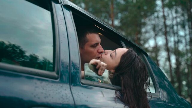 Amidst the serene embrace of nature, a couple leans in for a tender kiss from their car. Raindrops dance on the window, adding a magical touch to their romantic getaway.
