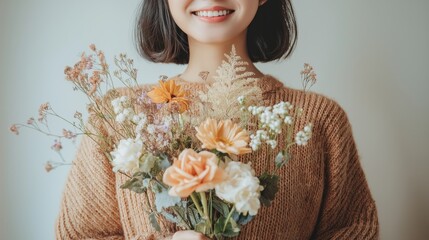 Fototapeta premium Close-up of a woman smiling while holding a bouquet of flowers, featuring soft diffused lighting against a neutral background
