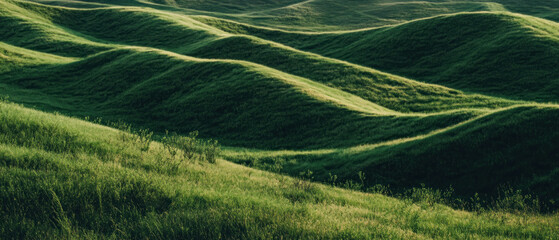 Cinematic pattern texture of rolling hills covered in lush green grass from a top view perspective