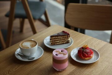 Aromatic coffee and delicious desserts served on wooden table in cafe