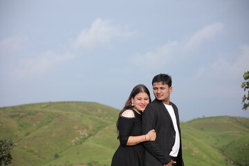 Obraz premium Happy young Indian couple in trendy clothes embracing against mountain under sky on sunny day