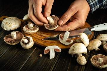 Hands deftly prepare fresh mushrooms on a wooden cutting board, showcasing the artistry of cooking...