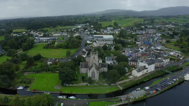 St Flannan's Cathedral, Killaloe, County Clare, Ireland, September 2021. Drone orbits counter clockwise while ascending above the River Shannon as stormy rain clouds draw closer to the medieval town.