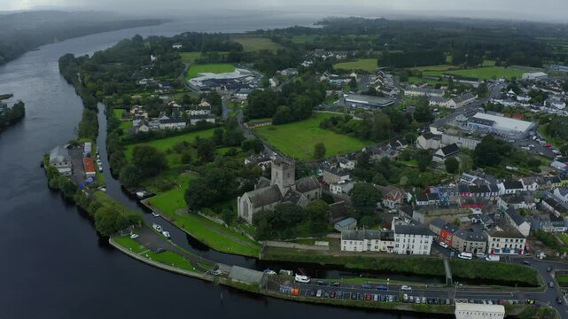 St Flannan's Cathedral, Killaloe, County Clare, Ireland, September 2021. Drone orbits counter clockwise at a high angle on a rainy day as a storm draws closer above the Shannon River.