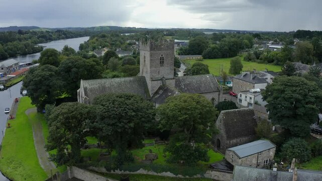 St Flannan's Cathedral, Killaloe, County Clare, Ireland, September 2021. Drone orbits counter clockwise around the tower and begins to pull backwards showcasing the River Shannon in the background.