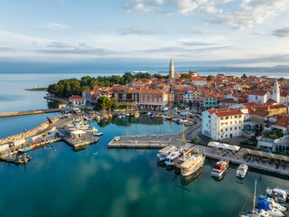 Aerial panoramic view of picturesque Izola town with the old town and buildings with red roofs, the main promenade, the marina with boats on Adriatic sea coast, Slovenia.