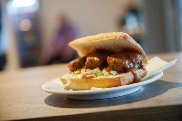 Close-up of a sandwich on a plate.  Meat and gravy, lettuce, on a sub roll.  Food photography.
