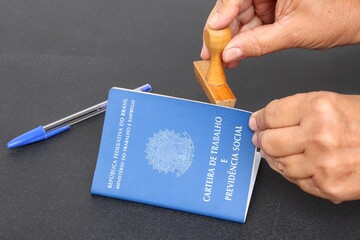 Signing the Brazilian work card. Translation: Federative Republic of Brazil, Ministry of Labor.| Brazilian Work Card (Carteira de Trabalho). Formal job concept.