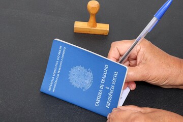 Signing the Brazilian work card. Translation: Federative Republic of Brazil, Ministry of Labor.| Brazilian Work Card (Carteira de Trabalho). Formal job concept.