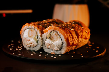 Fresh Sushi Rolls Presented on a Dark Plate With Sesame Seeds and Creamy Filling in a Dimly Lit Setting