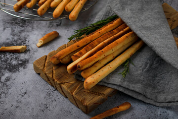 Grissini made of wheat flour with parmesan, rosemary and olive oil. Breadsticks on gray background....