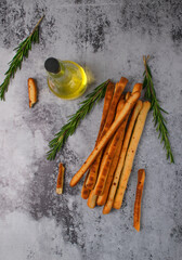 Grissini made of wheat flour with parmesan, rosemary and olive oil. Breadsticks on gray background....