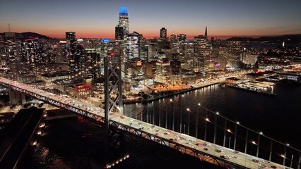 Fototapeta premium San Francisco Skyline In California United States. Illuminated Bridge. Bay Bridge Landscape. Sunset Cityscape. San Francisco Skyline In California United States. Landmark Viaduct. Highway Cars.