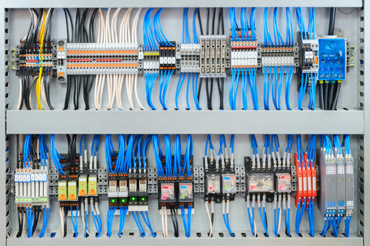 Large electrical panel with many wires and switches is blue and white. The panel is filled with various switches and wires, making it a complex and intricate piece of machinery