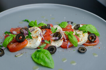 Mozzarella and tomato salad  with basil leaves  and black olives - Italian antipasti