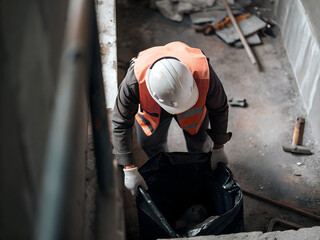 A worker removes construction waste into a black bag