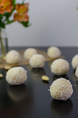 Homemade raw vegan coconut truffles - coconut balls aka Raffaello on the black table