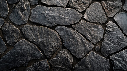 Fototapeta premium Close-up view of irregular dark slate stones arranged in a natural pattern on a textured surface