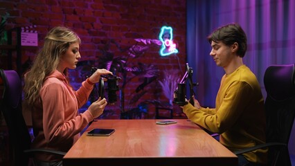 Man host and woman guest recording interview in loft podcast studio with microphones, creating...