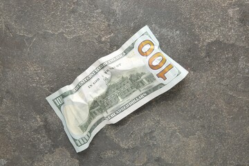 One crumpled dollar banknote on grey table, top view