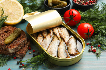 Tasty sprats in tin can served on light blue wooden table, closeup