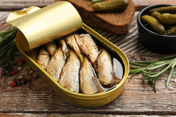 Tasty sprats in tin can served on wooden table, closeup