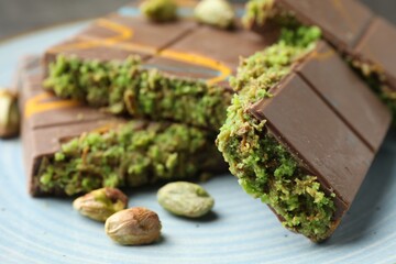 Pieces of Dubai chocolate bar with pistachios and knafeh on plate, closeup
