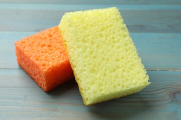 Soft sponges on light blue wooden table, closeup