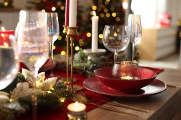 Christmas place setting with festive decor on wooden table in room, closeup