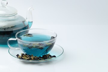Fototapeta premium Fresh butterfly pea flower tea and dry petals on white table, closeup. Space for text