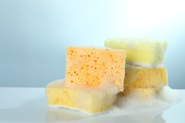 Sponges with foam on light table, closeup. Space for text