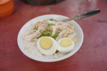 Chicken porridge seller is preparing order for customers. Bubur Ayam (Chicken Porridge), Indonesian Traditional Food.
