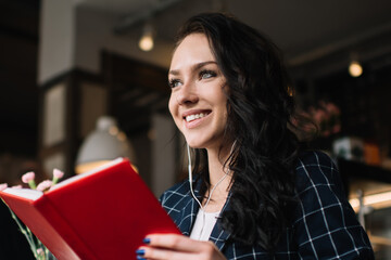 Pleased woman reading book during break in cafe
