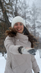 Obraz premium Portrait of a beautiful young woman in winter clothes. The woman smiles happily against the background of a snowy park
