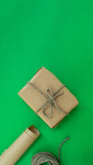 Christmas gift wrapping. Vertical background. Gift in craft paper, twine, paper on a green background.