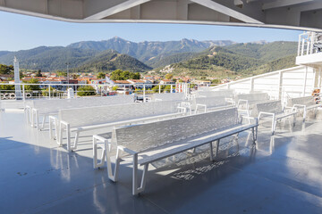Empty ferry deck seating with picturesque island views on a sunny summer day in Greece.