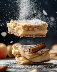 Delicious apple charlotte slices hover in mid-air, dusted with sugar and accompanied by cinnamon sticks. Warm tones and rustic elements enhance the inviting atmosphere of this homemade treat