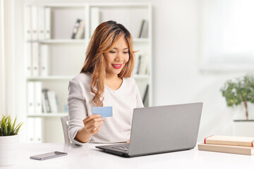 Asian woman paying bills from home with a laptop computer