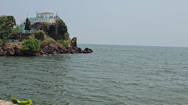 Dona Paula viewpoint A rocky cliff extending into the sea with pavilion atop it, surrounded by greenery,serves as a scenic viewpoint overlooking the Arabian Sea.