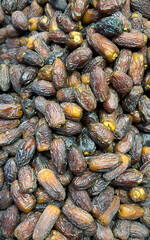 A close-up photograph of a large pile of dried dates and dates fruit