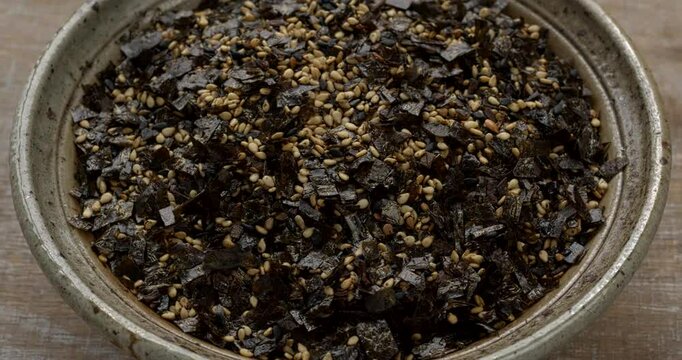 Homemade organic vegan Japanese seasoning with sesame seeds and seaweed in a bowl. Table spin. 