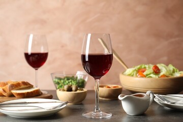 Red wine and delicious dinner served on grey table