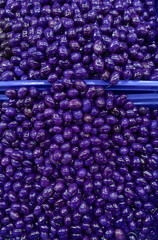 A close-up photograph of a large quantity of blueberry-flavored olives