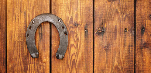 Front view of a wooden door with an iron lucky horseshoe for good luck. Concept for luck and fortune. A talisman superstition for luck.