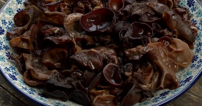 Whole dried and hydrated mun mushrooms in bowl. An ingredient of Chinese cuisine. Table spin. 