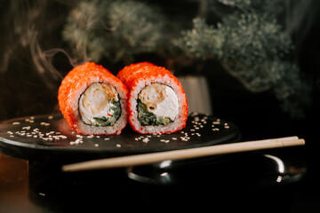 Fresh red sushi on a black board with chopsticks on a dark background. Set of rolls with caviar. Sushi concept