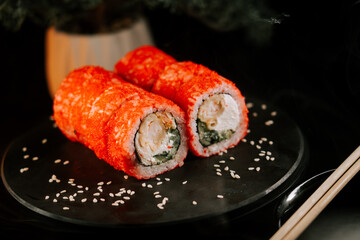 Fresh red sushi on a black board with chopsticks on a dark background. Set of rolls with caviar. Sushi concept